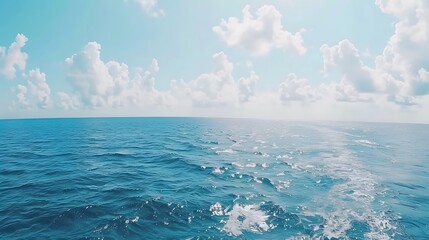 The vast open ocean stretches beneath a cloudy blue sky