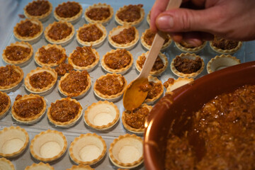 Hand with wooden spoon fills the meat canapes to serve at the celebration.