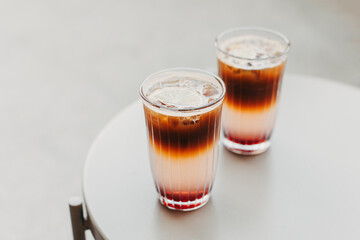 Two glasses of refreshing summer cocktail with lemon and ice on a table. Cocktail with ice, coffee and lemon slices.