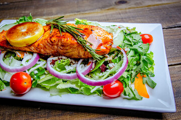 delicious and tasty grilled Salmon plate with cherry tomatoes, rosemary, and fresh onion rings