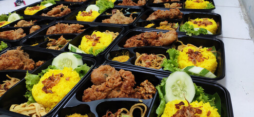 Prepared meals with turmeric yellow rice and fried chicken
