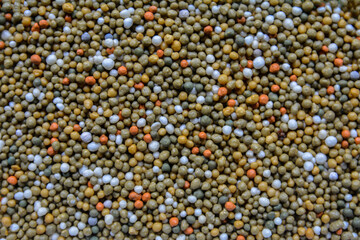 Colorful fertilizer granules in a bowl.