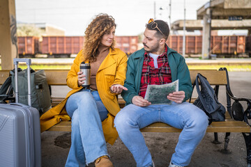 couple sit on bench and look at map and mobile phone for directions