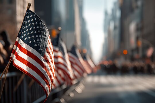 A patriotic display of American flags lining a city street, symbolizing national pride and unity, with blurred buildings in the background during a daytime parade event.
