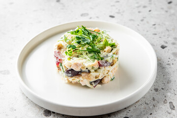 A beautifully layered salad with mixed vegetables, tender salmon, and creamy dressing, garnished with fresh microgreens. This dish offers a perfect balance of flavors and textures.