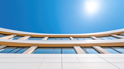 Obraz premium Modern building facade against a vibrant blue sky. Curved architecture with rows of windows and light beige accents