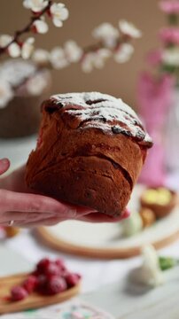A woman takes an Easter cruffin in her hands and breaks it, showing a fluffy, tender dough with a berry filling. cruffin with raspberry jam. Easter bread. Easter eggs and spring flowers
