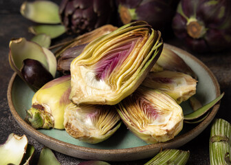 Plate full of cut purple raw artichokes closeup. Fresh italian vegetables from farmers market