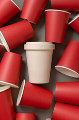 New red paper cups and beige reusable bamboo coffee cup on a gray top view, mockup