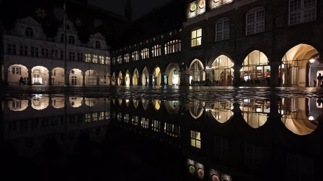 Lubeck, Germany: Panoramic footage of Market square and the ancient city hall in the Luebeck medieval old town in Germany at night in winter with a reflection after the rain