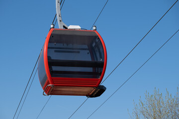 Close up of empty red gondola cabin suspended in blue sky