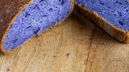 Freshly baked bread with a vibrant purple interior, cooked in blue Thai ancha tea, rests on a...