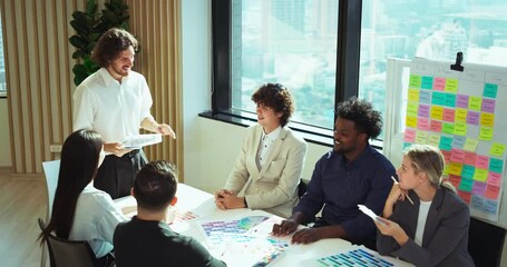 Group of diverse professionals gathered around a table discussing branding and color palette ideas in a bright modern office, highlighting teamwork, visual communication.