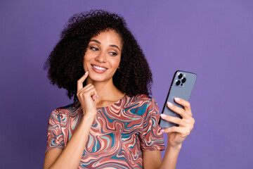 Young woman with curly black hair, wearing a colorful printed t-shirt, poses elegantly while...