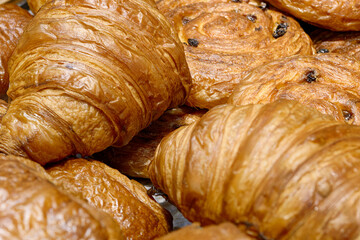 Various types of traditional pastries made from puff pastry - croissants and buns with raisins