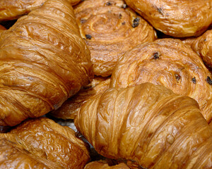 Various types of traditional pastries made from puff pastry - croissants and buns with raisins