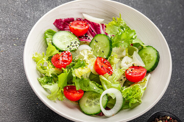 Vegetable salad tomato, cucumber, lettuce, green leaf lettuce, onion appetizer vegetable dish fresh gourmet food background rustic food top view copy space 
