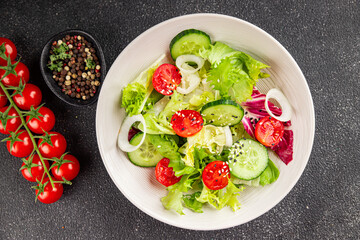 Vegetable salad tomato, cucumber, lettuce, green leaf lettuce, onion appetizer vegetable dish fresh gourmet food background rustic food top view copy space 