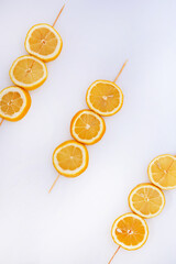 Fresh lemon slices arranged on wooden skewers over a white background. Minimalist citrus composition, perfect for food, drink or summer design themes.