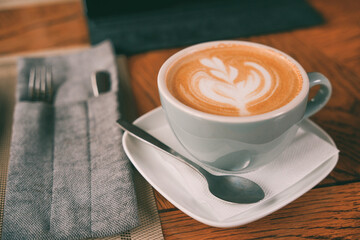 A mug of coffee on a plate with a spoon