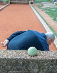 Man is bending over to pick up a ball