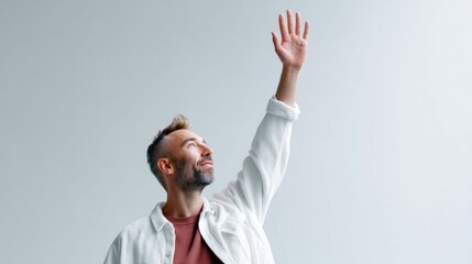 A man with his arm raised, reaching towards the sky, in a studio shot with soft light.