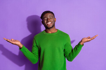 Young man with a happy expression in a green sweater against a vibrant purple background striking an expressive gesture. © deagreez