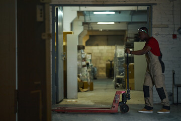 African American worker using trolley for load in workshop