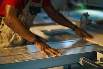 Close-up of worker doing wooden sign on lathe in workshop