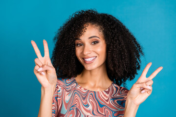 Smiling young woman with beautiful curly hair posing happily in a trendy patterned t-shirt against...