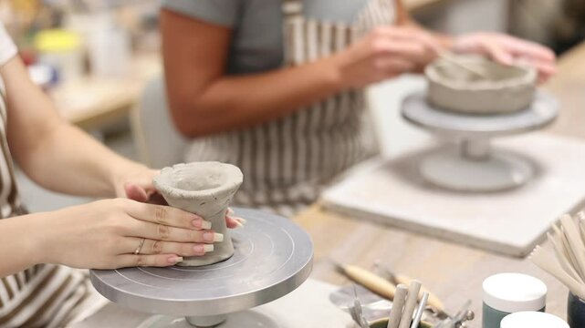 Female hands sculpting product from raw clay in ceramic workshop close-up