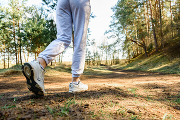 Fototapeta premium Rear view of a woman's legs in sportswear before running on early spring forest background.