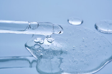 Pipette with serum on a blue background. Product texture.