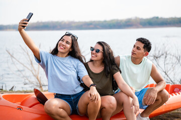 Group of latin hispanic friends having fun taking a selfie by the lake ready to go kayaking at...