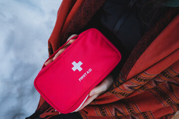 Naklejka premium A determined individual firmly holds onto a vivid red first aid kit, fully prepared to offer assistance to anyone requiring urgent medical care during a critical emergency situation