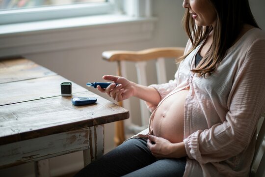 Pregnant Woman Monitoring Blood Sugar Level During Pregnancy At Home With Glucometer And Lancing Device