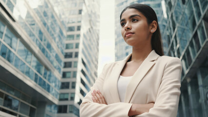 Confident woman standing in a modern urban environment with reflective glass buildings