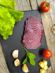 Thin slices of bacon lie on a sliced board