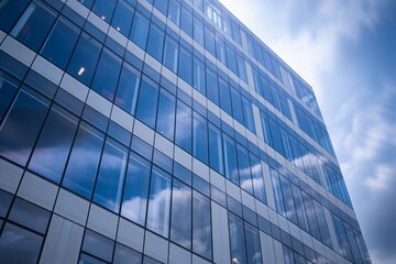 Modern Office Building With Blue Glass Facade Reflecting The Cloudy Sky In The Windows On A Bright Day