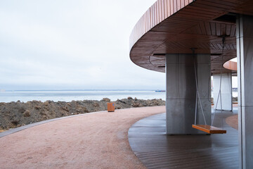 A walkway features swings suspended from a circular wooden structure, offering panoramic views of...