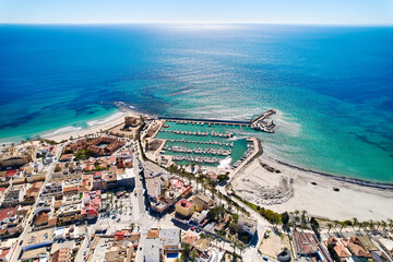 Aerial view coastal spanish town of Torre de la Horadada with houses rooftops, turquoise bay of...