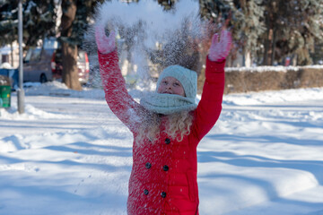  girl  throwing snow at sunny day. New Year and Christmas scene. child in the winter. Winter holidays concept. Blurred photo