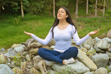 A young woman engages in the peaceful practice of mindfulness and meditation within a beautiful...