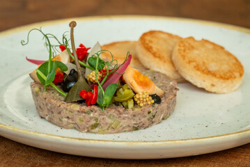 Gourmet meat tartare with pickled vegetables and toasted bread
