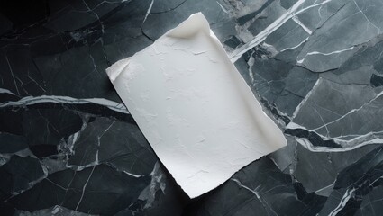 A sheet of empty white grunge paper positioned on a marble stone table from above, ideal for design use.