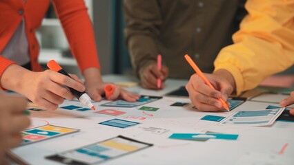 Diverse team members engage in a creative brainstorming session, using colorful markers to sketch...