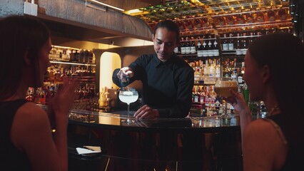 Asian smart bartender mixed vodka cocktail glass decorated flower on top serving to beautiful customer at luxurious counter bar making special drink. Refreshment alcohol nightlife luxury. Vinosity.