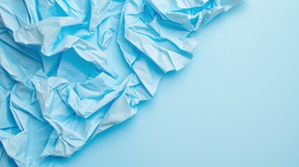 Obraz premium Slightly crumpled sheet of unfolded blue paper lying flat on soft blue background, texture revealed by side light, monochrome minimalism