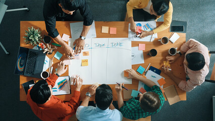 Top down aerial view of business team making scrum task board at meeting room. Group of people writing at paper and sticky notes for making kanban board to manage work flow. Top view. Convocation.