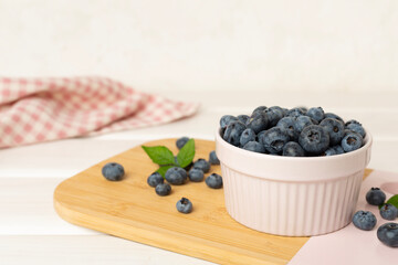 Bowl with fresh bright blueberries on wooden table
